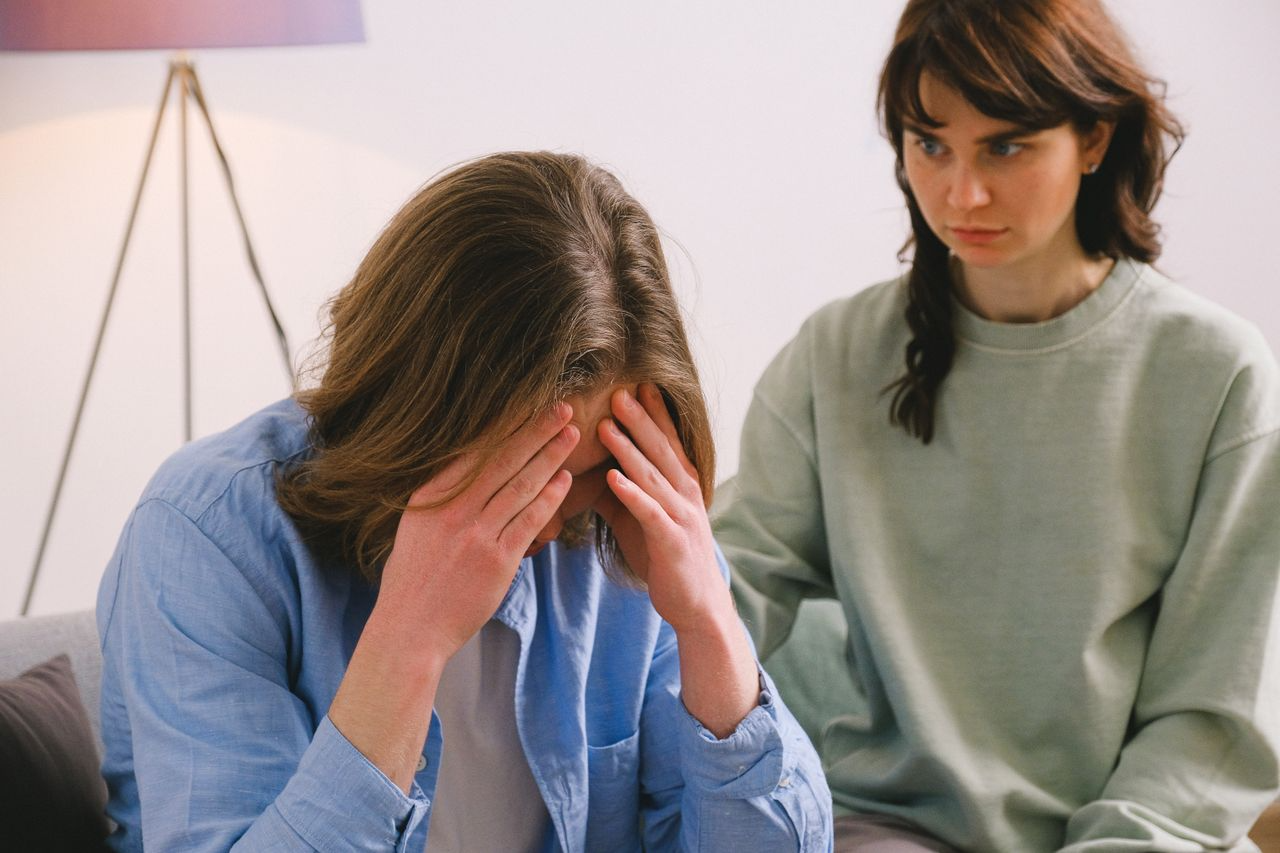 Homem preocupado com a mão na cabeça conversando com psicóloga tentando entender a diferença entre ansiedade normal ou patológica e qual está mais alinhada a sua realidade hoje